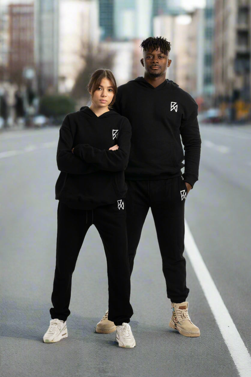 a man and woman standing wearing black hoody and sweat pants 