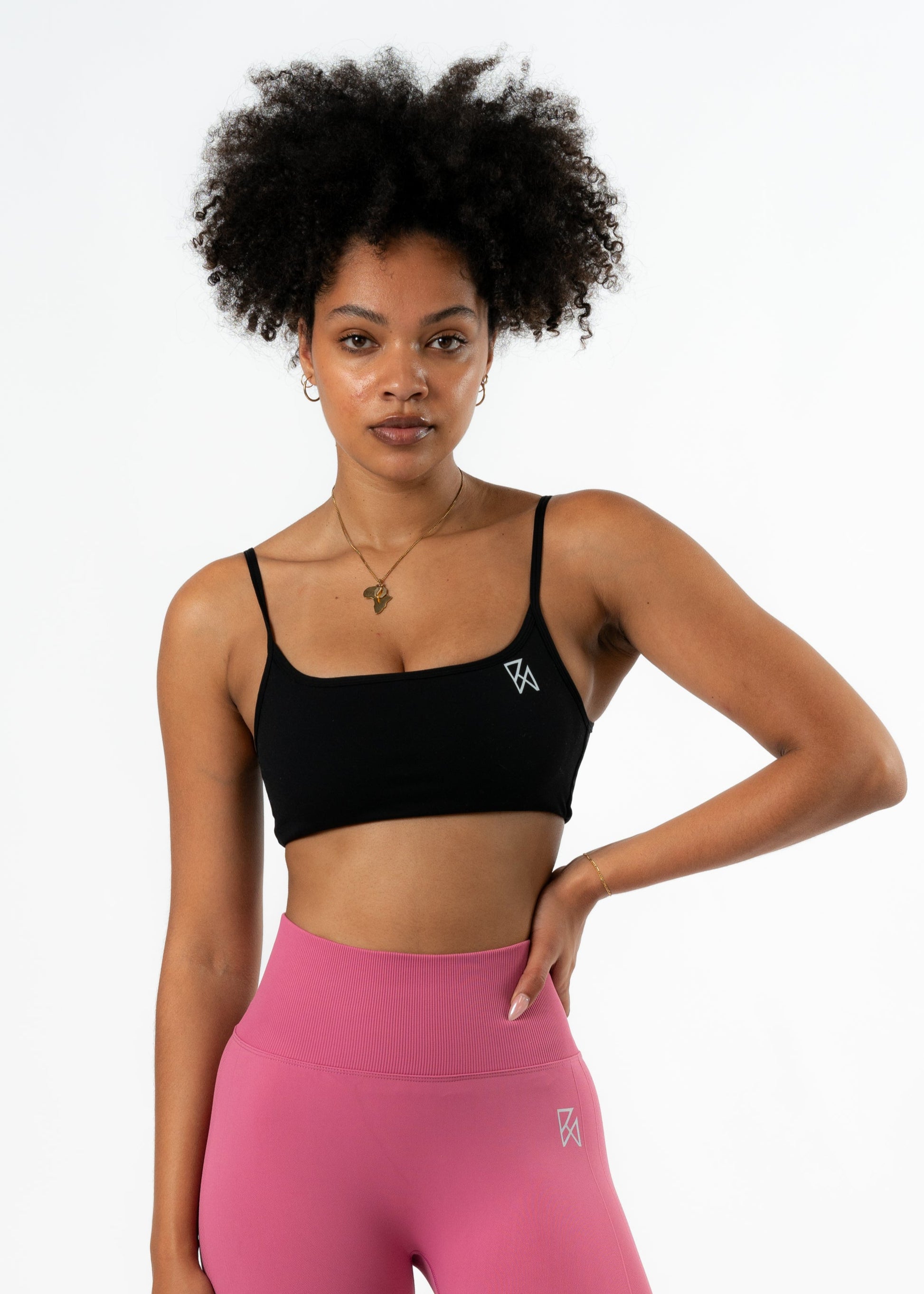 Woman wearing pink leggings and black sports bra on a white background
